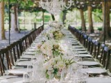 a neutral vineyard wedding reception with white blooms and greenery, white porcelain and crystal chandeliers is elegant and chic