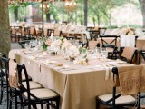 a cozy neutral wedding reception with tan and beige linens, neutral blooms, crystal chandeliers and beige chair covers for a perfect match