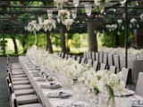 a white vineyard wedding reception with white blooms in glasses hanging down, neutral linens and white blooms on the table looks very sophisticated