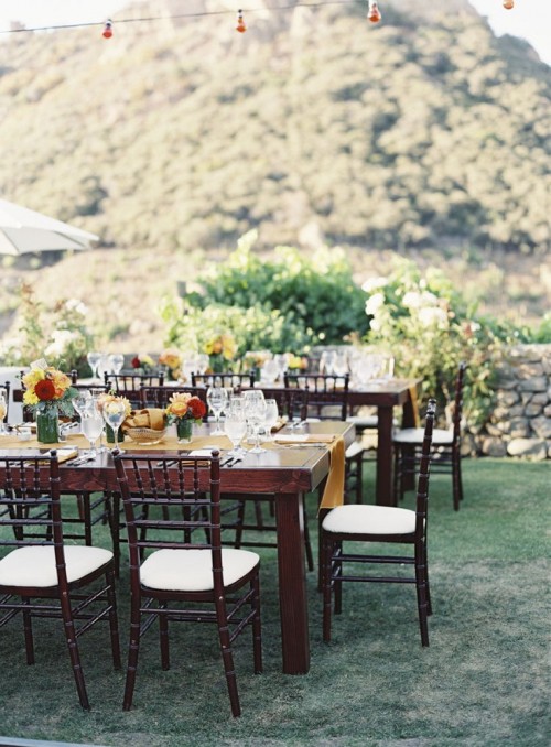 a chic wedding reception with bright table runners, bold blooms and greenery, white chairs
