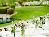 a neutral vineyard wedding reception with neutral linens, pink blooms and greenery and pillar candles plus a lovely greenery view
