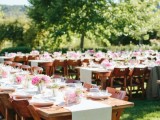 a vineyard wedding reception with greenery, neutral linens and pink blooms is a very cool and chic space with much natural light