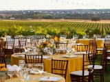 a colorful vineyard wedding reception with mustard tablecloths and yellow blooms and greenery plus a view of the vines and bold blooms