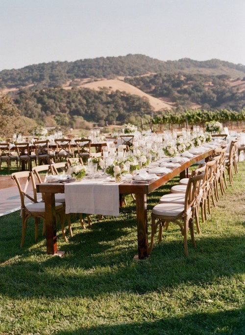 a neutral wedding reception with white linens, greenery and neutral blooms and a cool mountain view