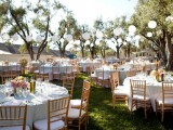 a stylish neutral vineyard wedding reception with lots of greenery around, with white linens and a white garland over the space