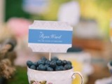 a vintage teacup filled with blueberries and with escort cards is a great wedding favor idea and escort card holder