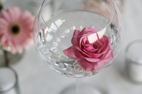 a clear glass with pearls and a pink rose is a budget-friendly and very refined summer wedding centerpiece