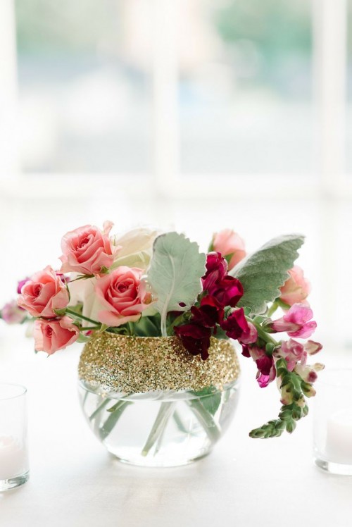 a clear vase with gold glitter and pink blooms and leaves looks chic, glam and bright and will accent your summer tablescape