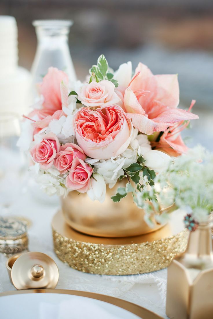a romantic summer wedding centerpiece of a gold vase, pink blooms, white flowers and leaves looks chic, glam and fresh