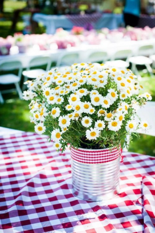 a rustic summer wedding centerpiece of a metal bucket, with daisies and a plaid wrap is a simple and very cute decoration