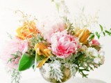a beautiful summer wedding centerpiece of a gold urn, orange, pink and white blooms and various greenery