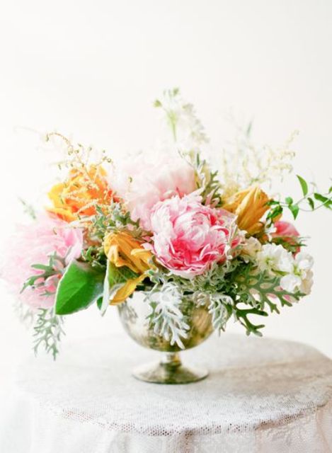 a beautiful summer wedding centerpiece of a gold urn, orange, pink and white blooms and various greenery