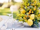 a super bold summer wedding centerpiece of green and orange blooms, foliage and citrus of various kinds screams summer and tropics