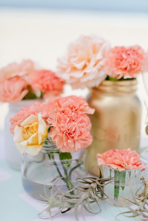 a vivacious summer wedding centerpiece of gold, white and clear vases and jars, blush, peachy and coral blooms is chic and stylish