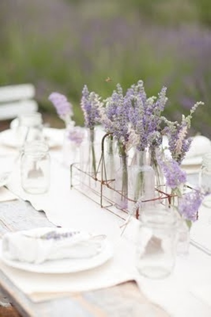 a chic and simple summer wedding centerpiece of a wire basket, clear vases with lavender and some lavender around is refined
