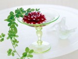 a green glass stand with a burgundy bloom and cascading greenery is a refined and chic summer wedding centerpiece
