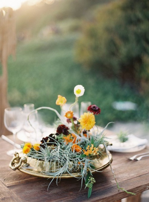 a whimsy wedding centerpiece of a gold bowl, yellow, orange and deep purple blooms and air plants will make your tablescape cooler
