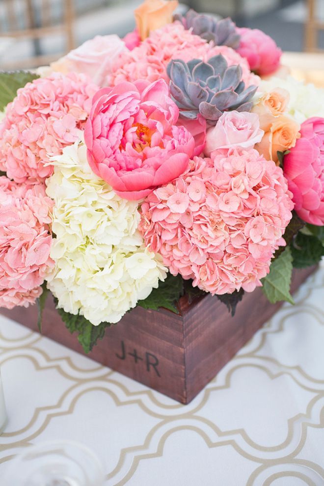 a dark stained box with pink, coral pink and white blooms and leaves is a vivid summer wedding centerpiece