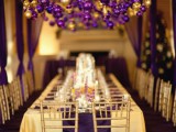 a purple and gold wedding reception with ornaments overhead looks bold, bright and colorful and very festive-like