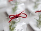 sheer square ornaments filled with faux snow, evergreens and with red bows are nice escort cards and favors