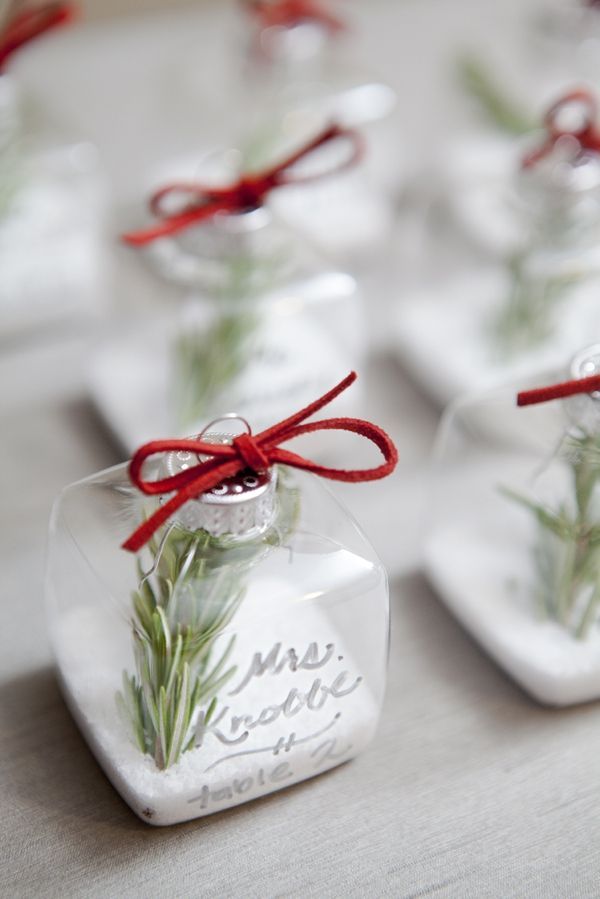 Sheer square ornaments filled with faux snow, evergreens and with red bows are nice escort cards and favors