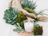 a driftwood wedding centerpiece of moss, succulents, driftwood and candles plus air plants for a coastal wedding