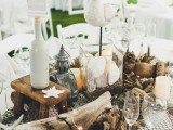 a cool beach wedding decoration of driftwood, candles, seashells, starfish, pebbles, fishnet and bottles
