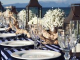 a driftwood wedding centerpiece with baby’s breath, white roses and candle lanterns is amazing for a nautical wedding