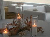 a beach wedding centerpiece of driftwood, candles and corals is easily DIYable and looks very beach-appropriate