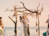 a driftwood wedding arch with white fabric is amazing for a coastal or beach wedding
