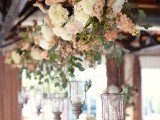 a driftwood wedding decoration of white and pastel blooms, greenery and candles hanging down is ideal for a beach or coastal wedding