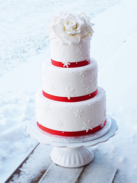 a white winter wedding cake decorated with red ribbon, with snowflakes and white roses on top is a fantastic idea for a winter wedding