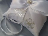 a white ring pillow with silver snowflakes and a bow on top is a gorgeous idea for a winter wedding