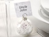 a clear glass ornament with candies inside and white snowflakes plus a silver snowflake card on top is a great idea for a winter wedding