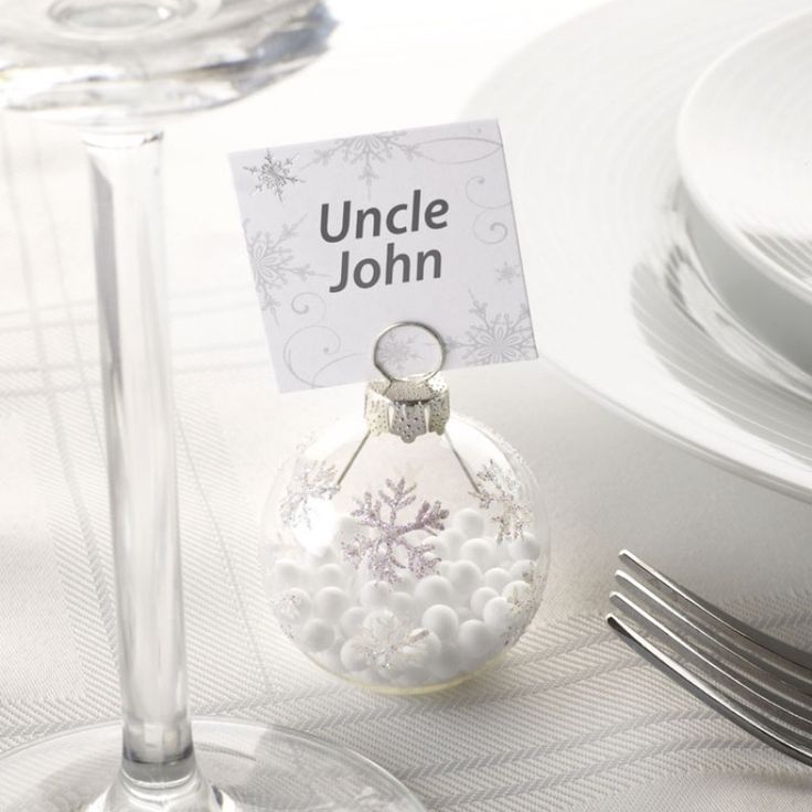 A clear glass ornament with candies inside and white snowflakes plus a silver snowflake card on top is a great idea for a winter wedding