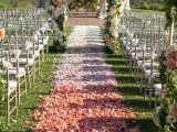 a fantastic wedding ceremony space done with ombre petals on the ground, with a pretty floral and greenery wedding arch is a chic solution to go for