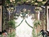 a chic wedding ceremony space done wiht greenery and lots of neutral blooms lining up the aisle and covering the ceiling is a wow solution