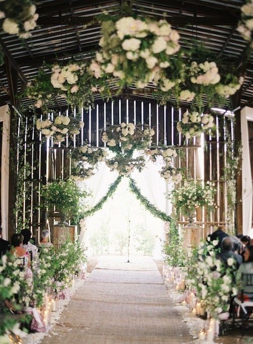 a chic wedding ceremony space done wiht greenery and lots of neutral blooms lining up the aisle and covering the ceiling is a wow solution