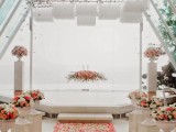 a jaw-dropping wedding ceremony space with lots of flower petals on the floor, urns with blooms, a floral arrangement as a wedding backdrop