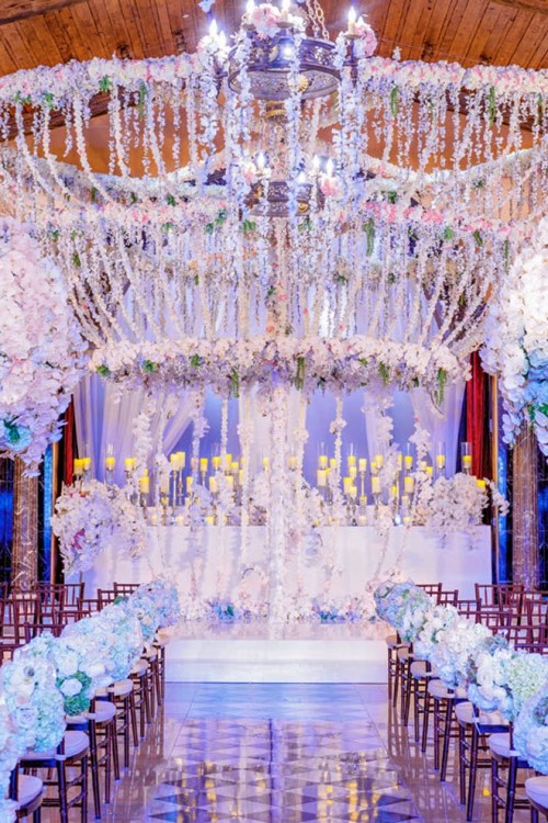 a fantastic lit up and flower-filled wedding ceremony space wiht lights, candles and flower chandeliers is amazing