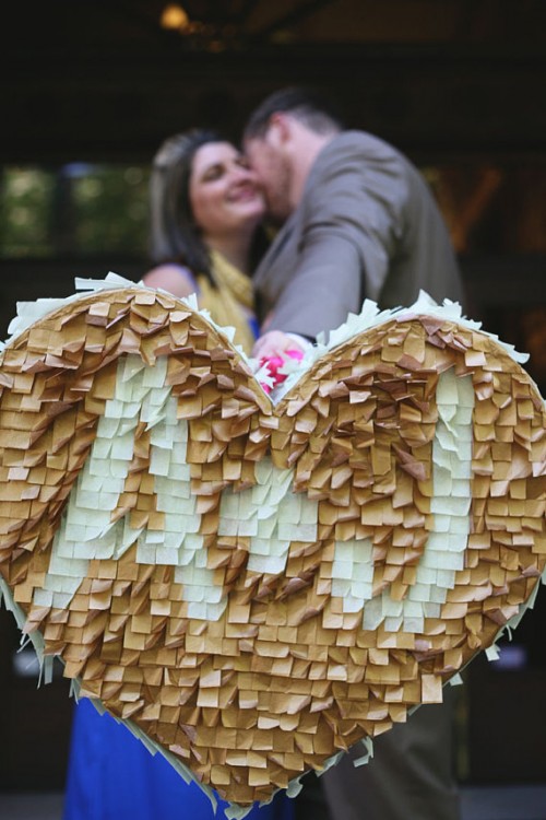 a tan and white fringe heart-shaped pinata as a creative wedding guest book, with monograms for more personalization is a lovely idea