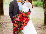 a super bold and oversized cascading wedding bouquet of pink, red and orange blooms and greenery is a bold statement for your wedding