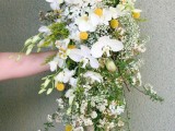 a chic and pretty lush cascading wedding bouquet with white blooms, billy balls, greenery and blooming branches is a chic and stylish solution to rock