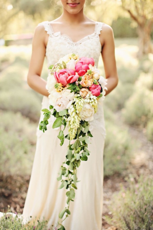 A delicate cascading wedding bouquet with pink and white peonies and greenery going down is a beautiful idea for spring or summer