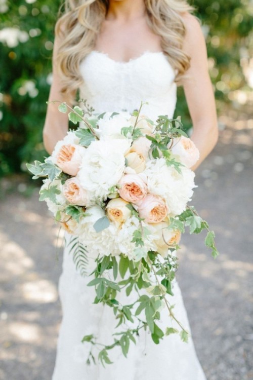 a super lush cascade wedding bouquet of white peonies and blush peony roses plus cascading greenery is a refined and stylish idea for a neutral or pastel wedding