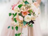 a lush pastel wedding bouquet with neutral and pastel blooms plus cascading greenery is a stylish idea for a spring or summer wedding