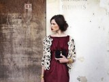 a burgundy knee dress with draping, a lace jacket with long sleeves and an embellished clutch