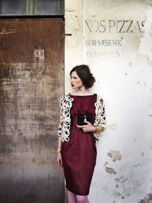 a burgundy knee dress with draping, a lace jacket with long sleeves and an embellished clutch