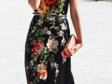 a black silk maxi dress with colorful embroidered florals, short sleeves, blue shoes and a red clutch