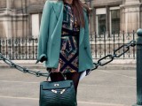 a colorful fitting mini dress, a green blazer, an emerald bag and black shoes with embellishments